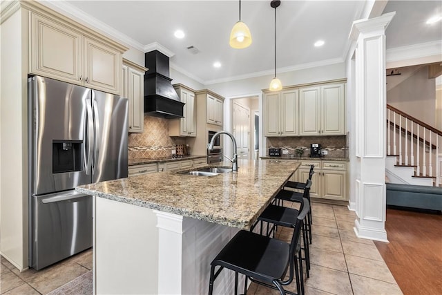 kitchen with stainless steel fridge with ice dispenser, decorative columns, custom range hood, and cream cabinetry
