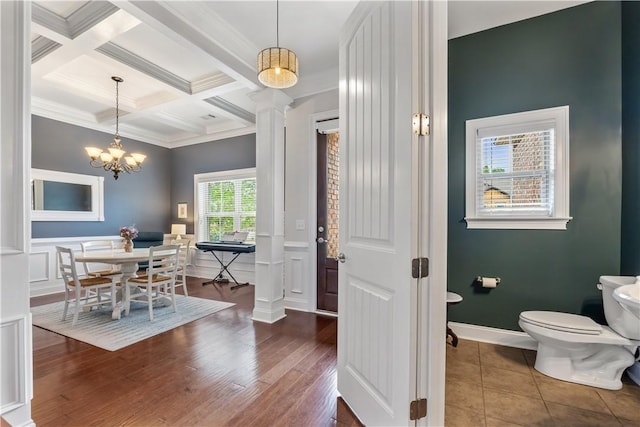 dining area featuring crown molding, beam ceiling, a notable chandelier, coffered ceiling, and ornate columns