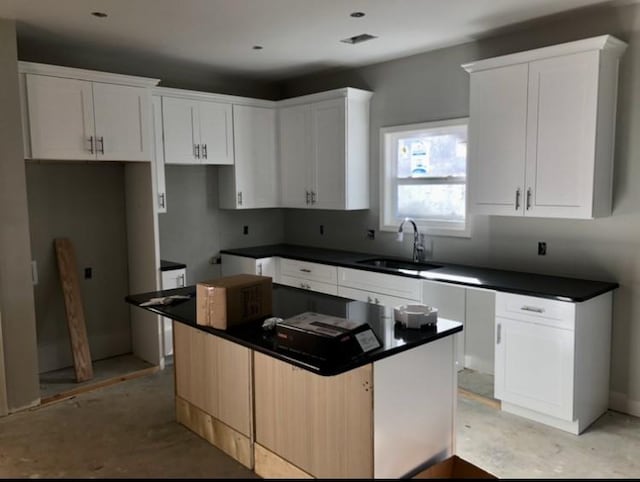 kitchen featuring a kitchen island, white cabinetry, and sink