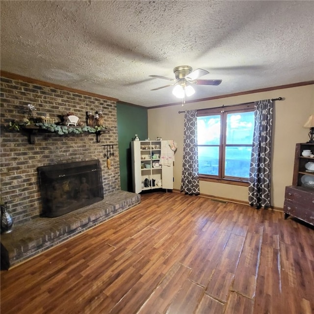 unfurnished living room featuring ceiling fan, a brick fireplace, crown molding, hardwood / wood-style floors, and a textured ceiling