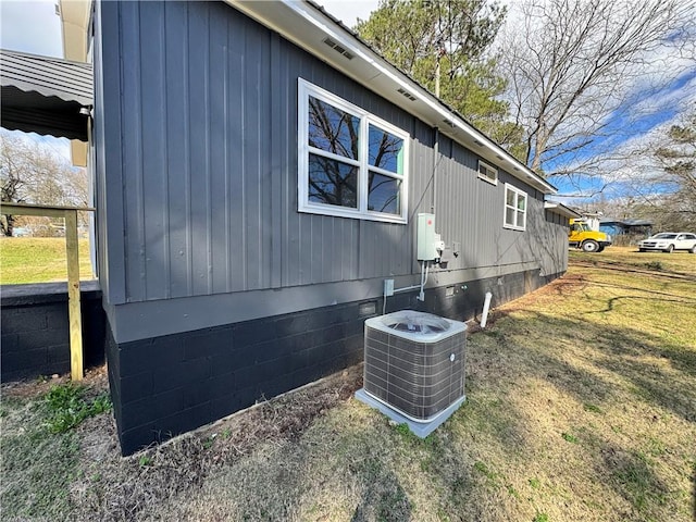 view of side of home with central AC unit, crawl space, and a lawn