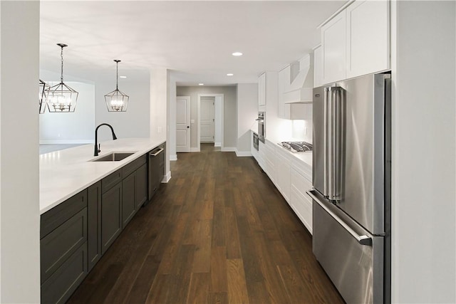 kitchen featuring premium range hood, sink, decorative light fixtures, white cabinetry, and stainless steel appliances