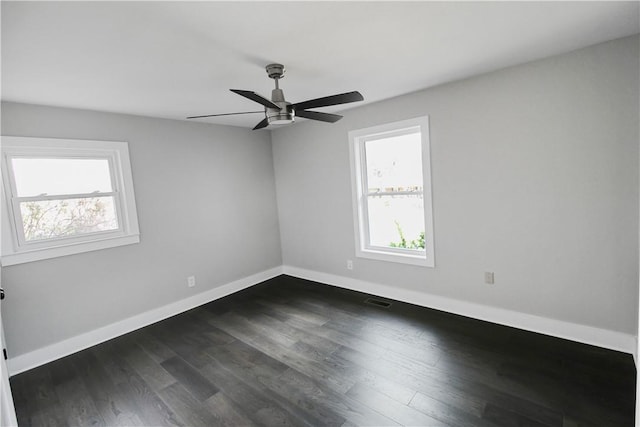 empty room with plenty of natural light, ceiling fan, and dark wood-type flooring