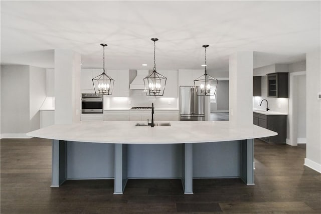 kitchen featuring sink, wall oven, high end refrigerator, premium range hood, and pendant lighting