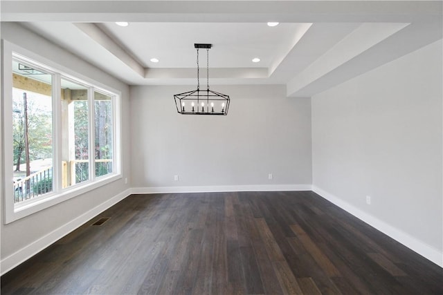 spare room featuring dark hardwood / wood-style flooring and a tray ceiling