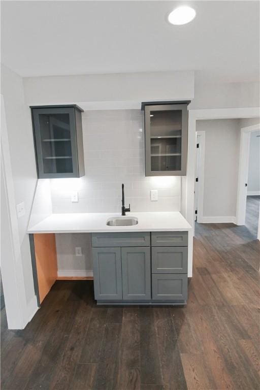 kitchen featuring dark hardwood / wood-style floors, tasteful backsplash, gray cabinetry, and sink