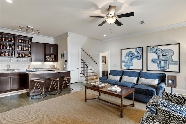 living room featuring ceiling fan, ornamental molding, and indoor wet bar