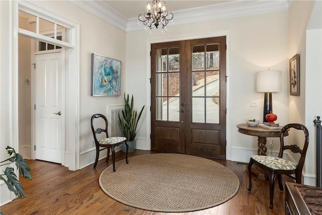 foyer featuring an inviting chandelier, dark hardwood / wood-style floors, ornamental molding, and french doors