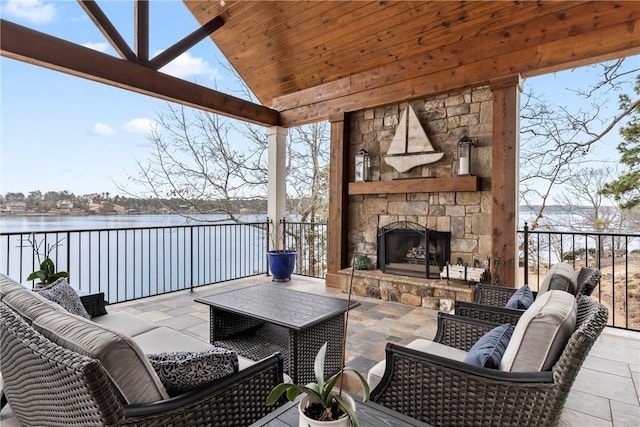 view of patio featuring an outdoor living space with a fireplace and a water view