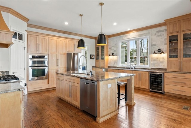 kitchen featuring pendant lighting, wine cooler, a kitchen island with sink, stainless steel appliances, and light stone countertops