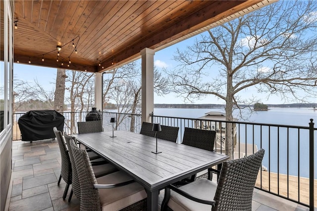 wooden terrace with area for grilling, a patio, and a water view