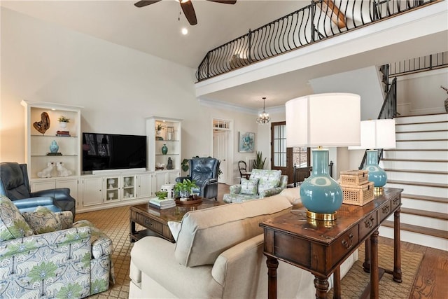 living room with crown molding, ceiling fan with notable chandelier, and a high ceiling