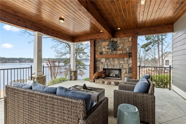 view of patio / terrace with a water view and an outdoor living space with a fireplace