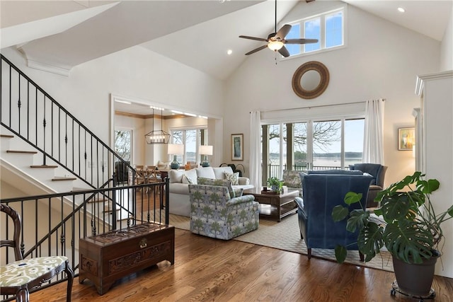 living room featuring hardwood / wood-style flooring, ceiling fan with notable chandelier, and high vaulted ceiling