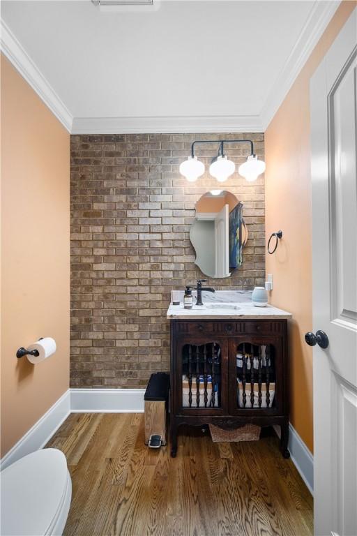 1579 Alex Ave, Auburn, AL 36830 - bathroom featuring baseboards, wood finished floors, ornamental molding, vanity, and brick wall