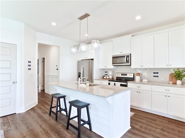 0104 Bradley Ln, Auburn, AL 36830 - kitchen with stainless steel appliances, a kitchen island with sink, a kitchen bar, dark wood-style flooring, and recessed lighting