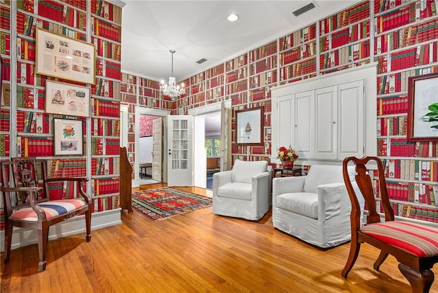 sitting room with a chandelier, wood-type flooring, and ornamental molding