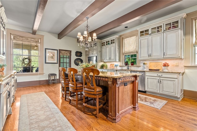 kitchen with light stone countertops, beam ceiling, dishwasher, a chandelier, and a kitchen island