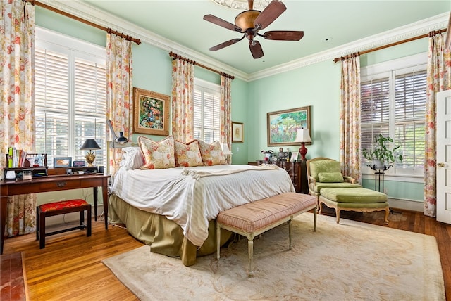 bedroom featuring ceiling fan, wood-type flooring, crown molding, and multiple windows