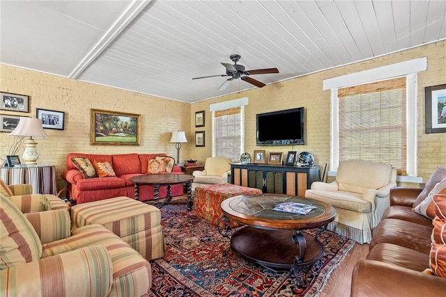 living room featuring wood ceiling, ceiling fan, and brick wall