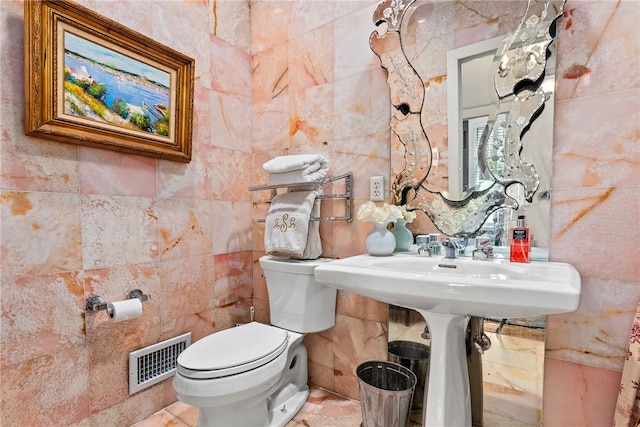 bathroom with toilet and tile walls