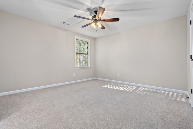 spare room with carpet floors, visible vents, baseboards, and a ceiling fan