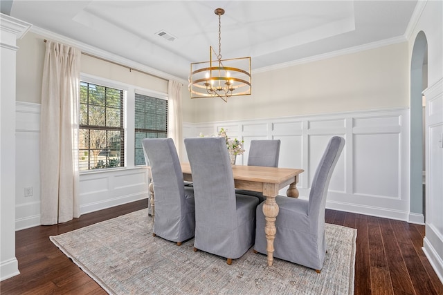 dining space with visible vents, a raised ceiling, dark wood-style floors, a decorative wall, and a notable chandelier