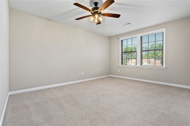 carpeted empty room with ceiling fan, visible vents, and baseboards