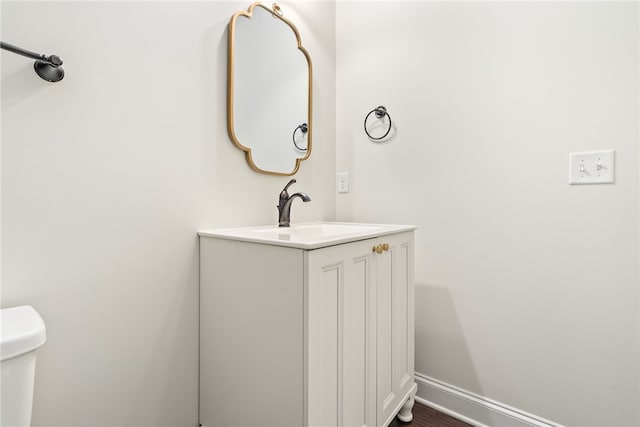 bathroom with toilet, vanity, and baseboards