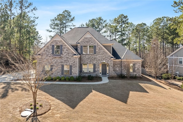 view of front of home featuring brick siding and roof with shingles