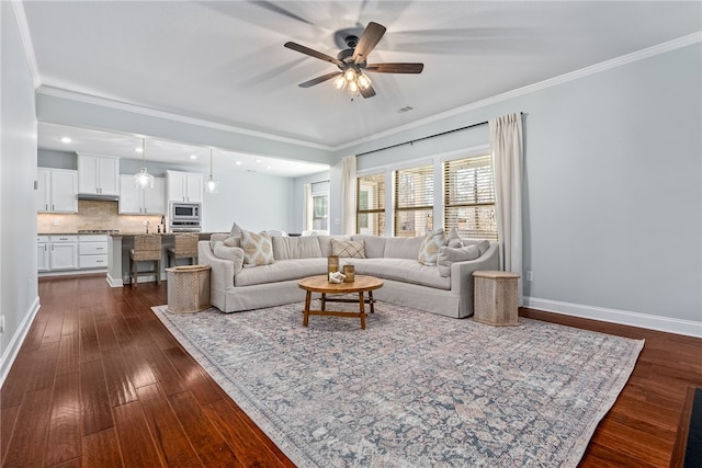 living room featuring a ceiling fan, baseboards, dark wood finished floors, and crown molding