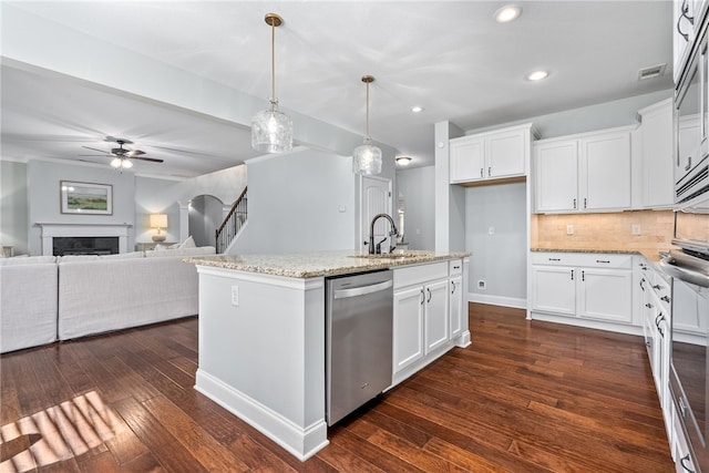 kitchen featuring a fireplace, a sink, stainless steel dishwasher, light stone countertops, and dark wood-style floors