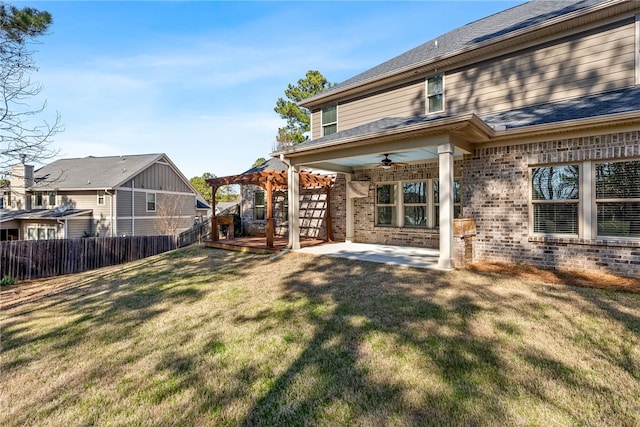 rear view of house featuring a ceiling fan, a lawn, fence, a pergola, and brick siding