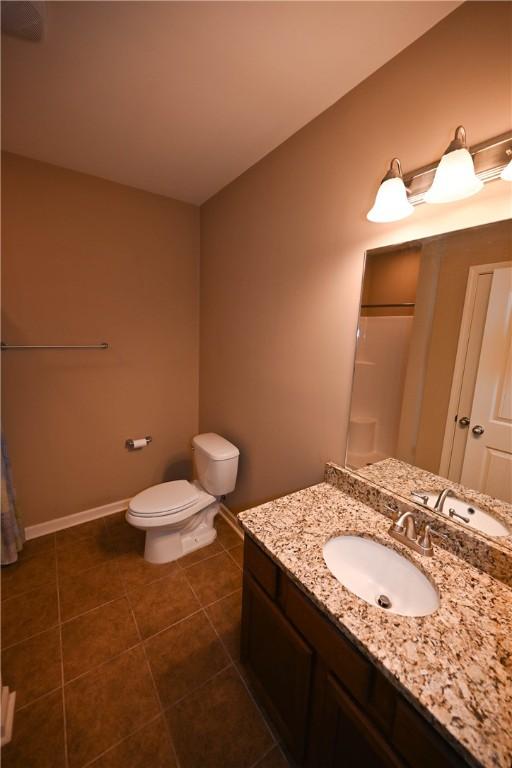 bathroom featuring vanity, a shower, tile patterned floors, and toilet