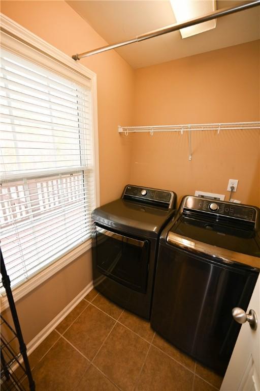 clothes washing area featuring separate washer and dryer and dark tile patterned flooring