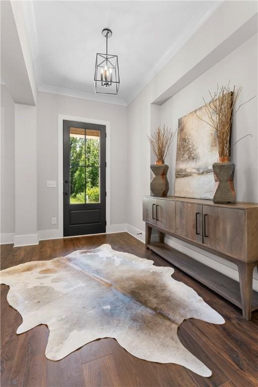 foyer entrance featuring baseboards, ornamental molding, a chandelier, and wood finished floors