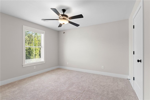 carpeted spare room featuring baseboards and a ceiling fan