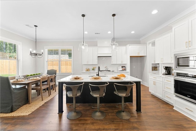 kitchen featuring appliances with stainless steel finishes, light countertops, white cabinetry, a center island with sink, and recessed lighting