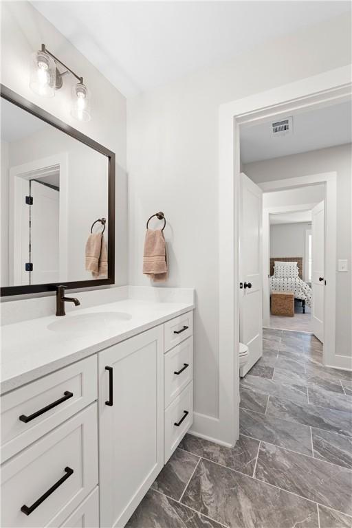 bathroom with vanity, toilet, baseboards, and marble look tile flooring