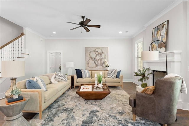 living area featuring wood finished floors, ceiling fan, stairs, a high end fireplace, and ornamental molding