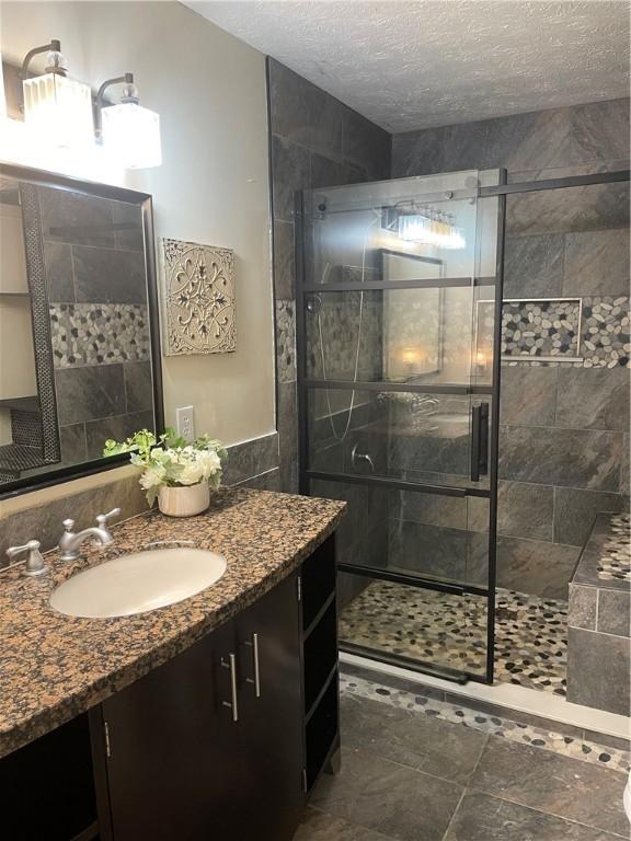 bathroom featuring an enclosed shower, a textured ceiling, and vanity