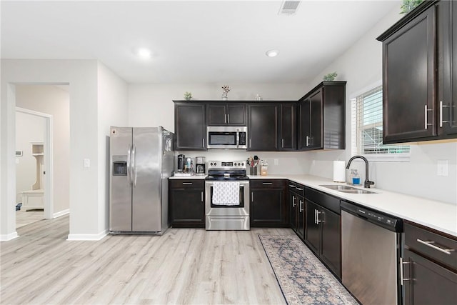 kitchen featuring dark brown cabinetry, stainless steel appliances, light hardwood / wood-style flooring, and sink