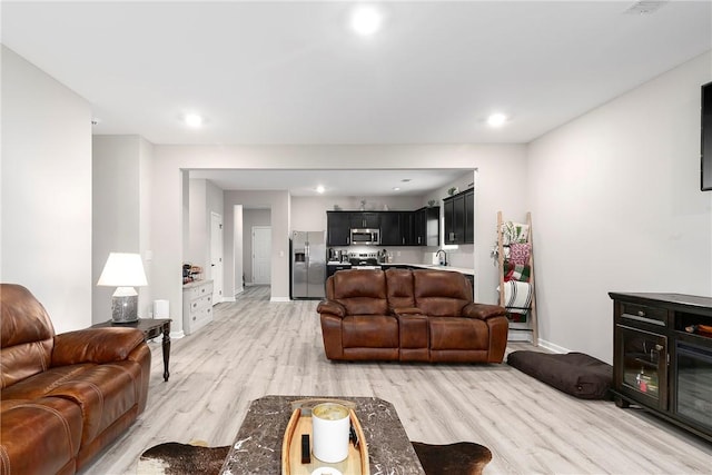 living room featuring sink and light hardwood / wood-style flooring