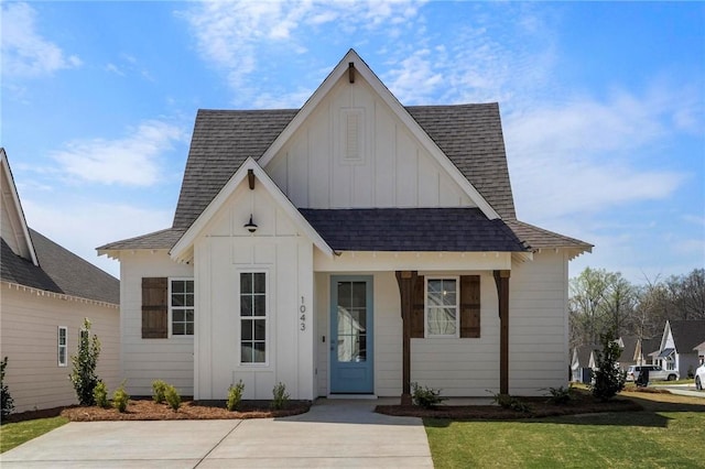 view of front of house with roof with shingles, board and batten siding, and a front yard