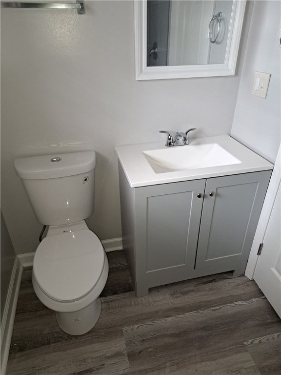 bathroom featuring wood finished floors, vanity, toilet, and baseboards