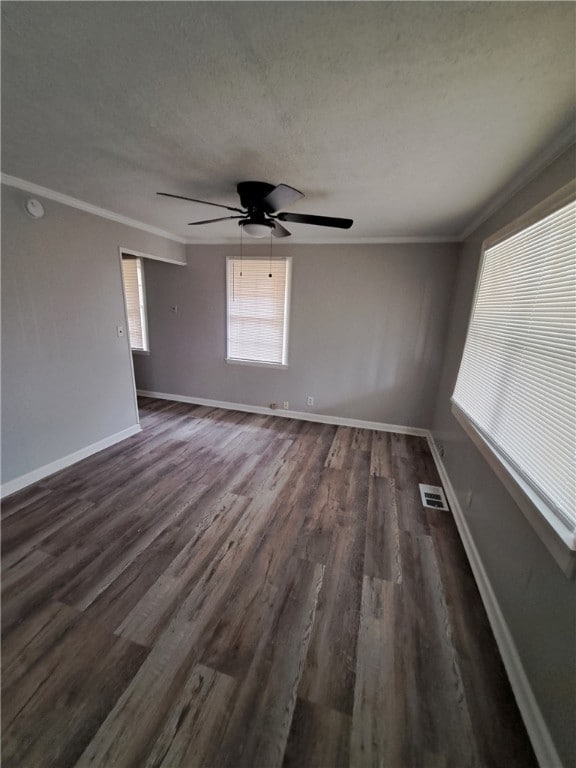 spare room featuring ornamental molding, dark wood-type flooring, visible vents, and baseboards