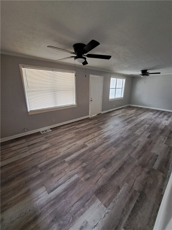 spare room featuring ceiling fan, a textured ceiling, visible vents, baseboards, and dark wood-style floors