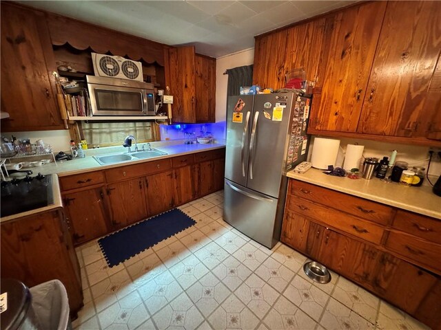 108 Carr St, Tallassee, AL 36078 - kitchen with appliances with stainless steel finishes, a sink, light countertops, brown cabinetry, and light flooring