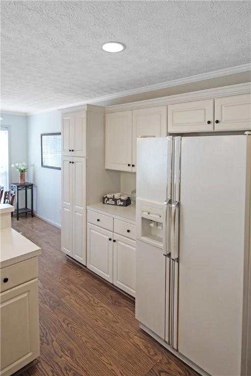kitchen with white fridge with ice dispenser, light countertops, dark wood-type flooring, and white cabinetry