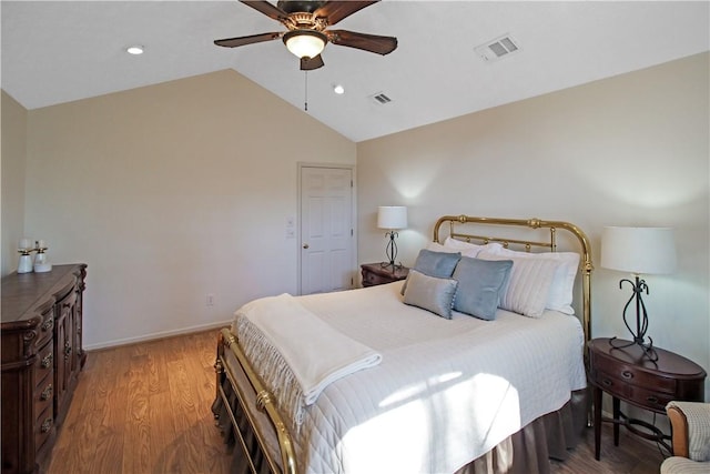 bedroom with vaulted ceiling, wood finished floors, visible vents, and baseboards